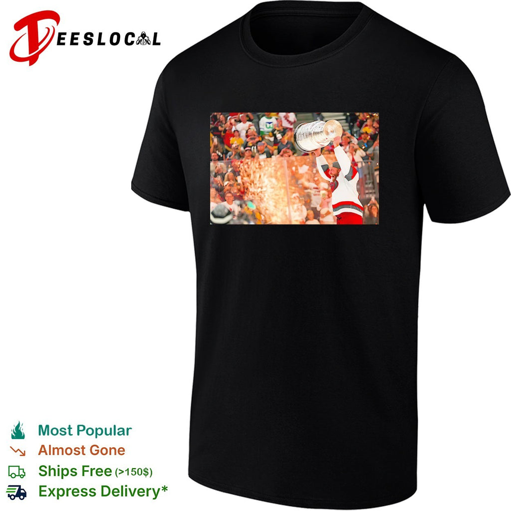 Carolina Hurricanes player hoisting Stanley Cup above head crowd fireworks triumphant moment shirt